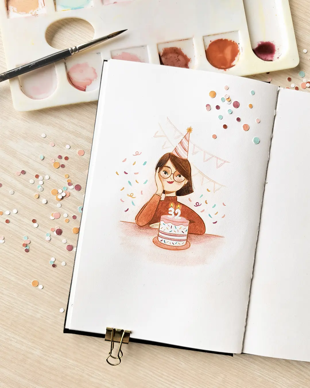 Page de carnet de croquis avec l'illustration d'une femme avec un chapeau pointu devant un gâteau d'anniversaire.