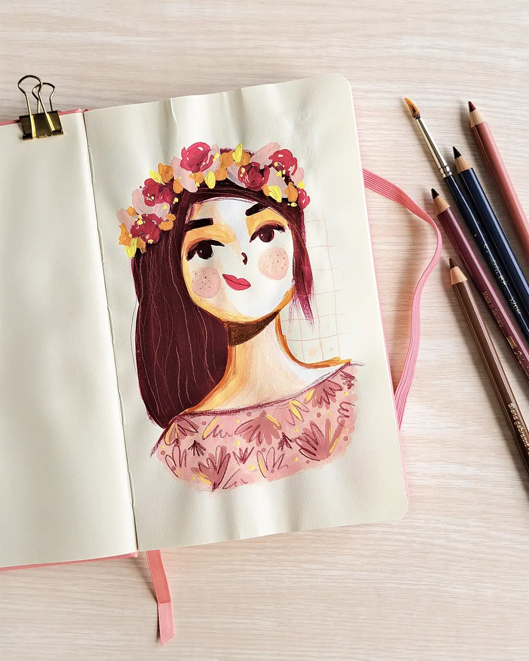 Page de carnet de croquis avec l'illustration d'une femme portant une couronne de fleurs sur sa tête et un chemisier à motifs.