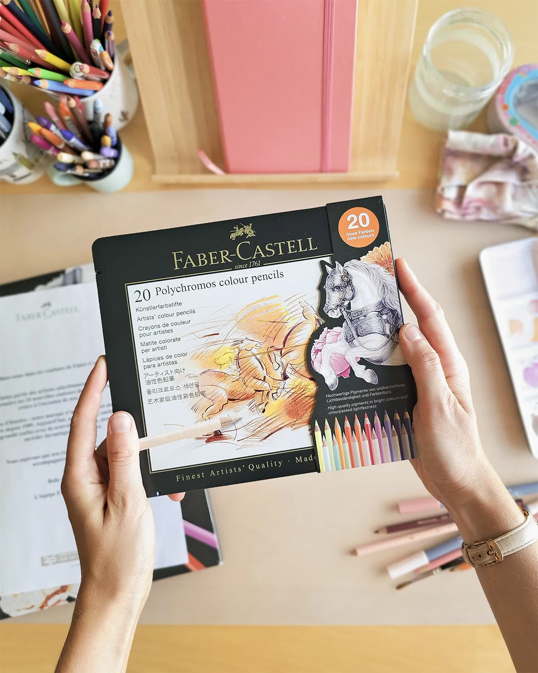 Illustratrice tenant dans ses mains la nouvelle boîte de crayons de couleurs Polychromos de la marque Faber-Castell.